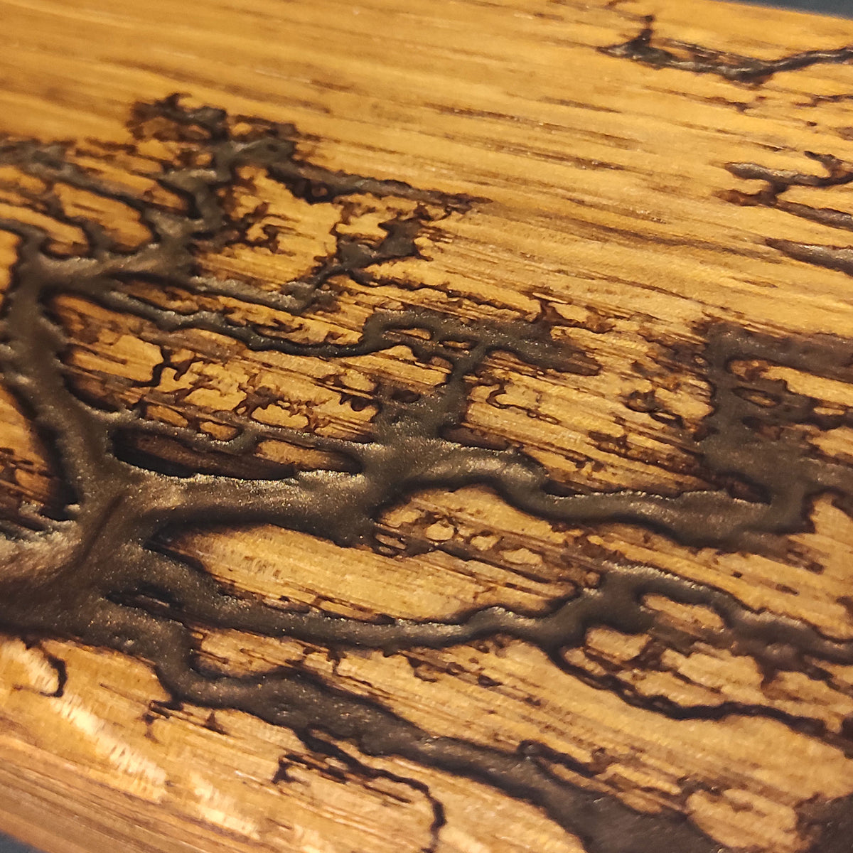 Lichtenberg-Gravur in Bronze Braun mit Metallicpigmenten auf Eiche